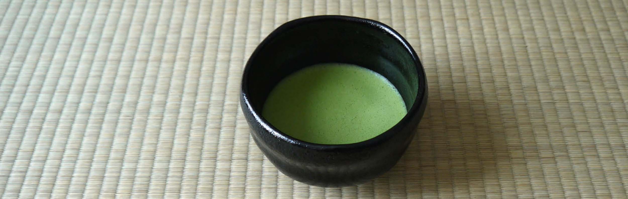 A bowl of matcha sits on a tatami mat